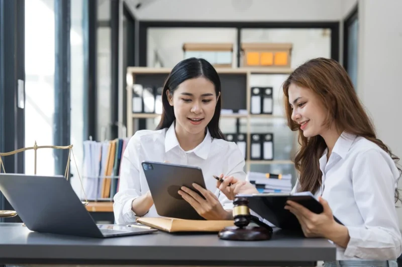 Two colleagues reviewing a tablet and documents together at a desk