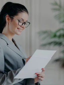 A consultant in a grey blazer and glasses reading a printed document