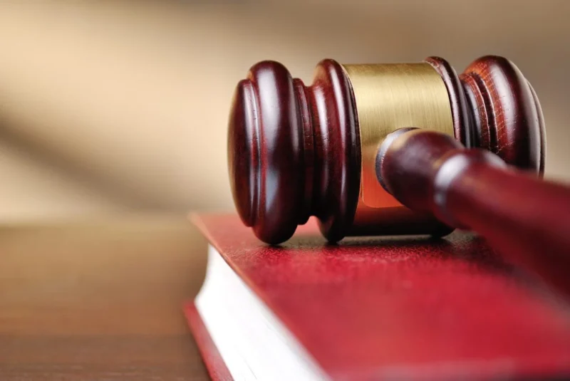 A wooden gavel resting on a red law book