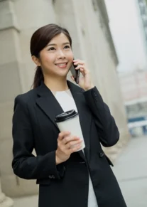 A legal professional on a mobile phone outside an office building, holding a coffee cup