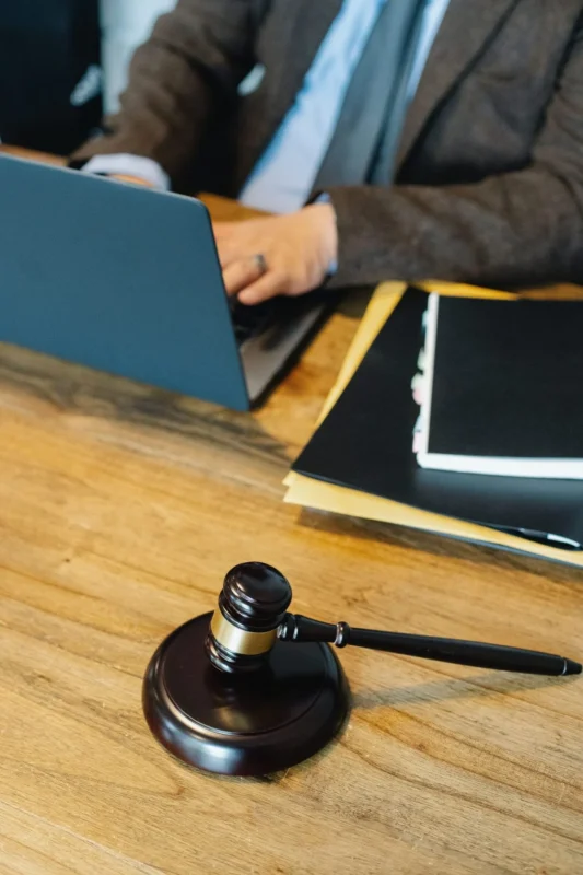 Brass scales of justice and a gavel on a desk beside a law book
