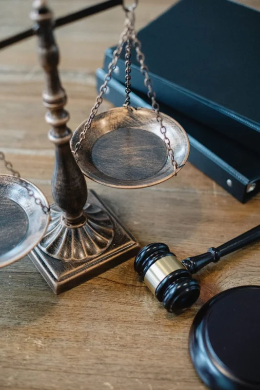 Brass scales of justice on a desk by a window, gavel alongside