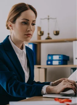 A solicitor working at a laptop beside a set of brass scales of justice