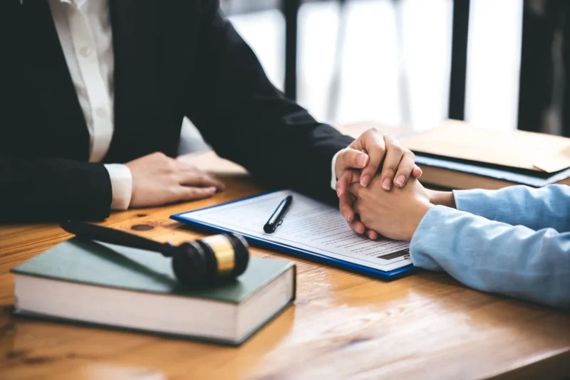 A solicitor and a client seated at a desk with a document and gavel