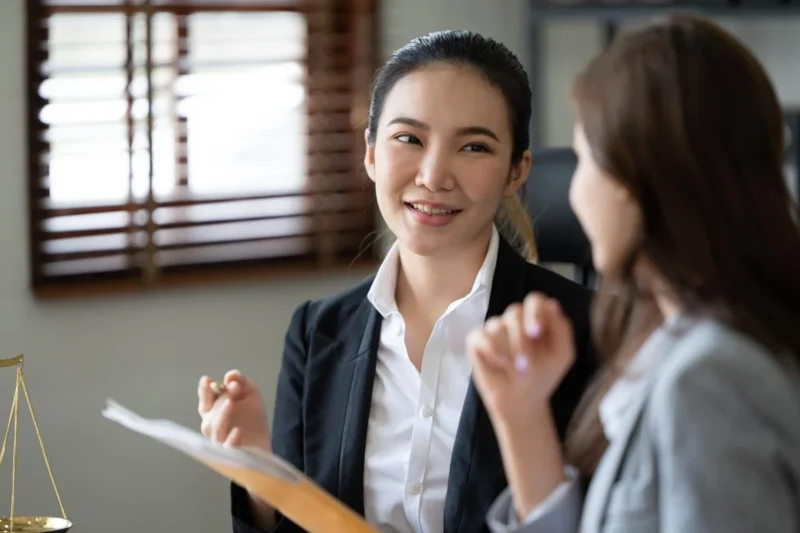 A solicitor in a dark blazer writing notes while reading a book